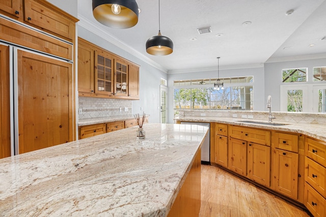 kitchen featuring brown cabinets, a sink, visible vents, and crown molding