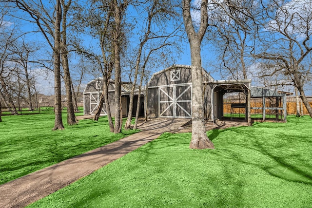 exterior space with a barn, fence, and an outbuilding