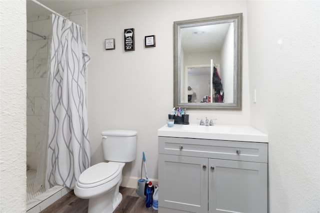 full bathroom featuring toilet, a stall shower, wood finished floors, and vanity