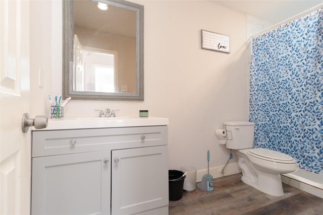 bathroom featuring baseboards, a shower with shower curtain, toilet, wood finished floors, and vanity