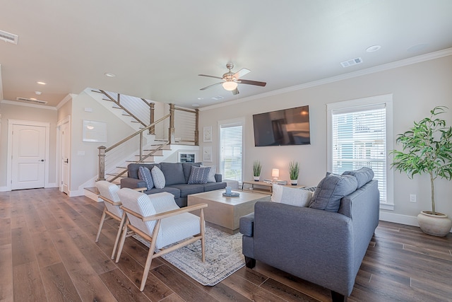 living area featuring dark wood-type flooring, visible vents, crown molding, and stairs