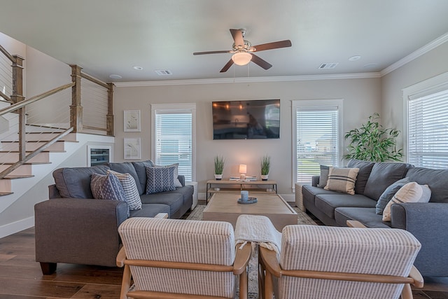 living area with wood finished floors, visible vents, baseboards, stairway, and crown molding