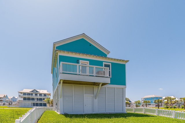 rear view of house with a lawn, a fenced backyard, and a balcony