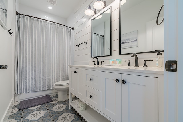 full bath with visible vents, a sink, toilet, and double vanity