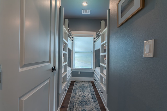 interior space featuring dark wood-style floors, a textured wall, visible vents, and baseboards