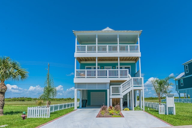 coastal inspired home with a garage, concrete driveway, fence, and a balcony