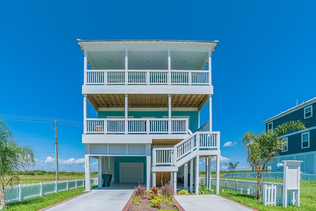 raised beach house with a garage, concrete driveway, and fence