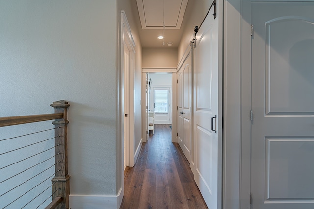 hallway featuring dark wood-style floors, attic access, and baseboards