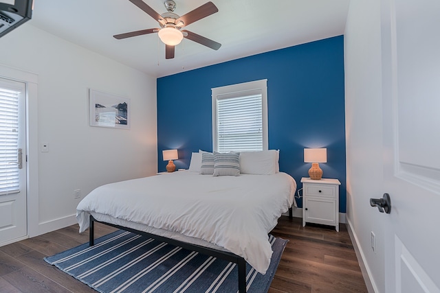 bedroom with dark wood-style floors, a ceiling fan, and baseboards