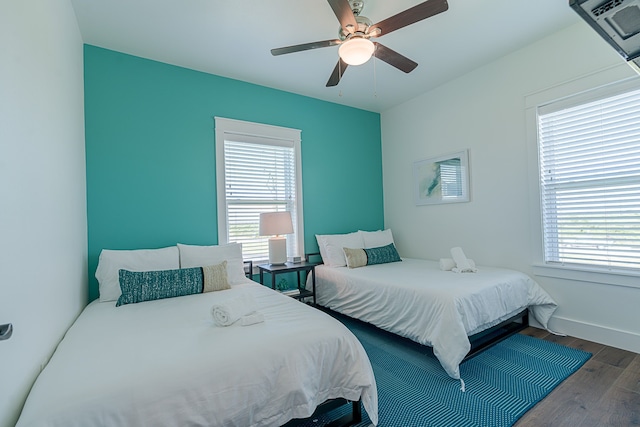 bedroom with dark wood-type flooring, multiple windows, ceiling fan, and baseboards