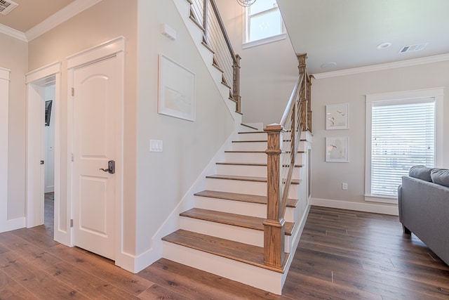 staircase featuring baseboards, visible vents, hardwood / wood-style flooring, and crown molding