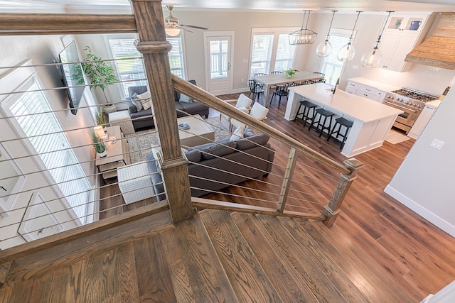 stairs featuring ceiling fan with notable chandelier, wood finished floors, and baseboards