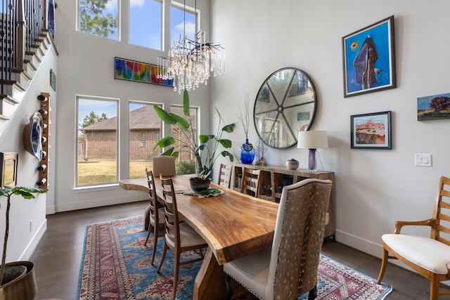 dining room with baseboards, stairway, wood finished floors, an inviting chandelier, and a high ceiling