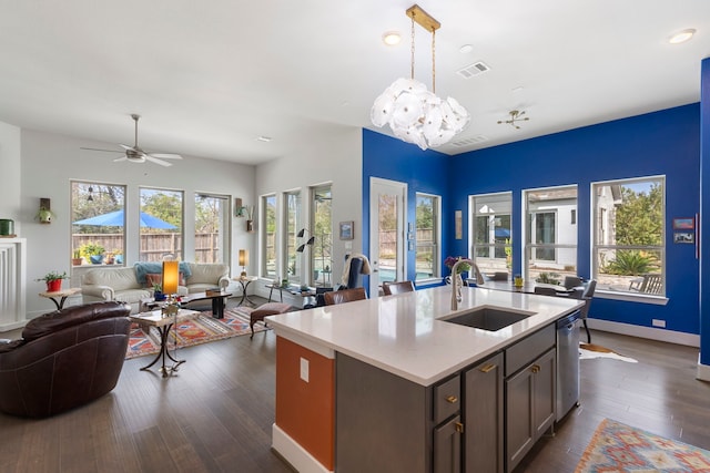 kitchen with dark wood-style floors, decorative light fixtures, visible vents, open floor plan, and a sink