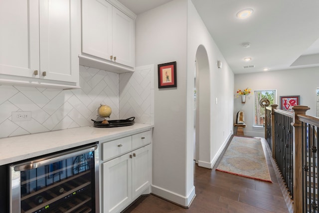 bar featuring arched walkways, wine cooler, dark wood-style flooring, baseboards, and tasteful backsplash