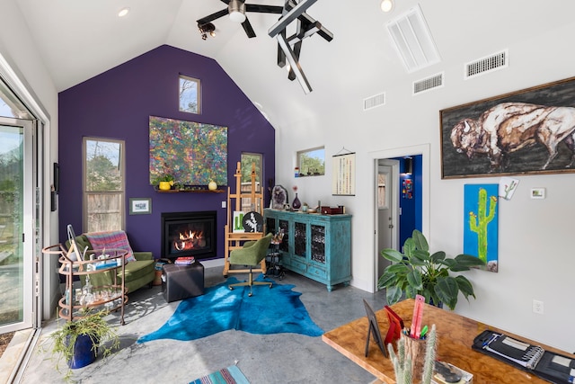 living area with finished concrete floors, a glass covered fireplace, visible vents, and high vaulted ceiling