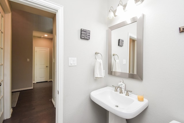 bathroom with a sink, baseboards, and wood finished floors