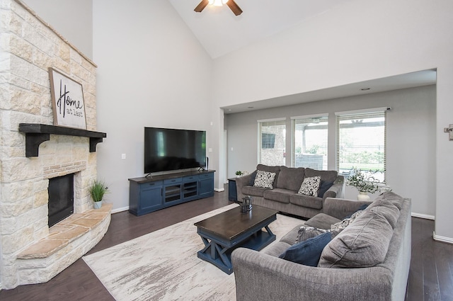 living room with high vaulted ceiling, a fireplace, baseboards, and wood finished floors