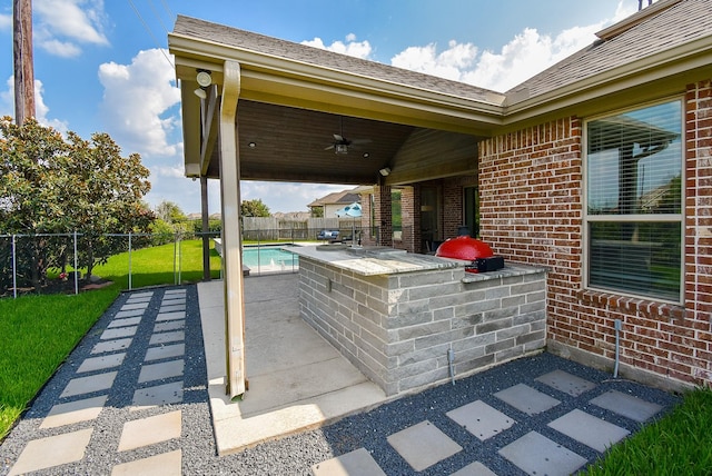 view of patio with a fenced backyard, an outdoor kitchen, and a ceiling fan