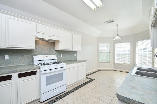 kitchen featuring light tile patterned flooring, under cabinet range hood, white range with gas stovetop, a sink, and a tray ceiling