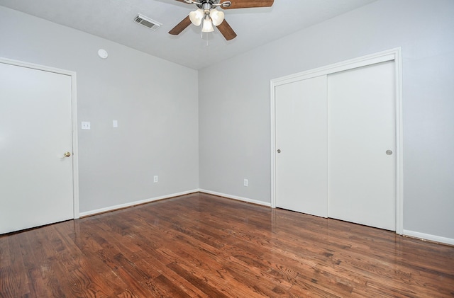 unfurnished bedroom featuring ceiling fan, wood finished floors, visible vents, baseboards, and a closet