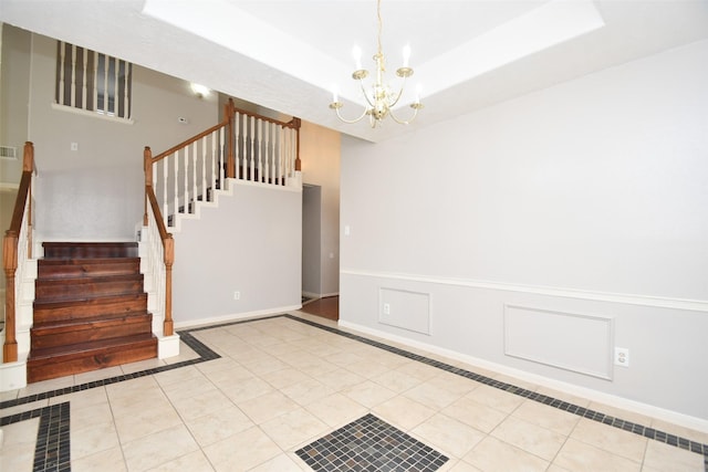 stairway with a raised ceiling, visible vents, wainscoting, a chandelier, and tile patterned floors