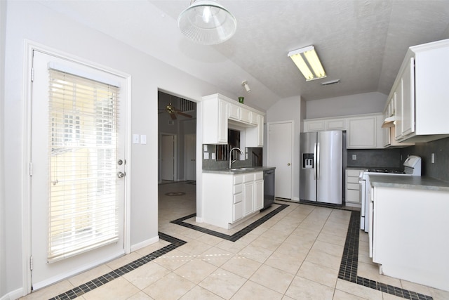 kitchen with light tile patterned floors, black dishwasher, vaulted ceiling, gas range gas stove, and stainless steel fridge