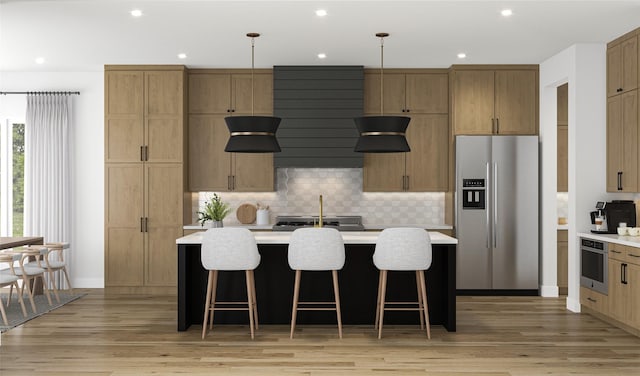 kitchen with light wood finished floors, light countertops, a center island with sink, decorative backsplash, and appliances with stainless steel finishes