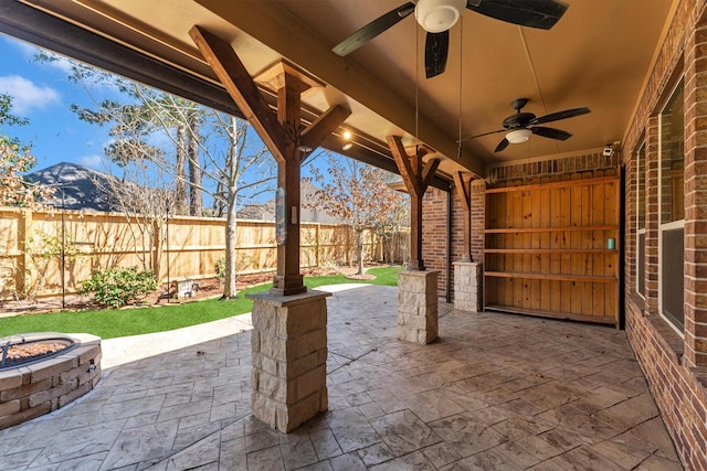 view of patio / terrace featuring a fenced backyard, ceiling fan, and a fire pit