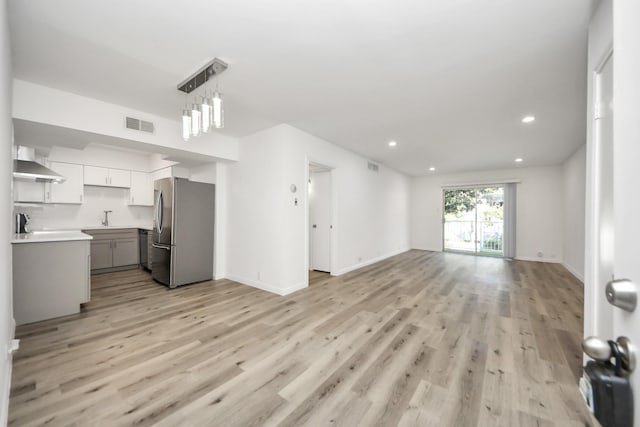 living area featuring baseboards, light wood-style flooring, visible vents, and recessed lighting