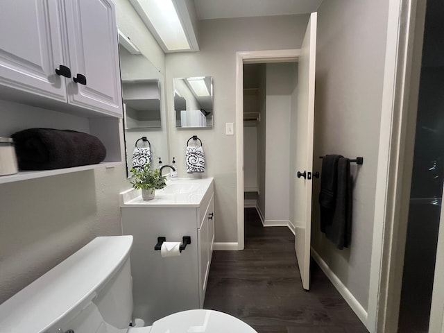 bathroom featuring toilet, baseboards, wood finished floors, and vanity