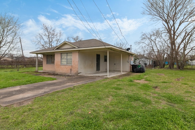 back of house with concrete driveway, brick siding, fence, and a lawn