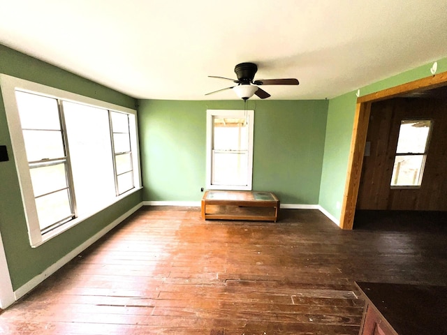 empty room featuring wood-type flooring, baseboards, and a ceiling fan