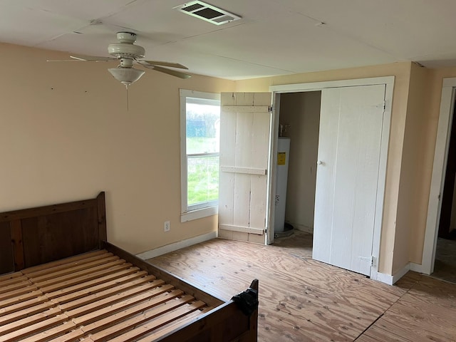 unfurnished bedroom with baseboards, water heater, visible vents, and a ceiling fan