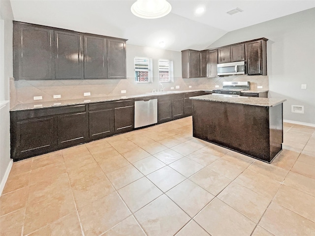 kitchen featuring visible vents, lofted ceiling, a sink, stainless steel appliances, and backsplash