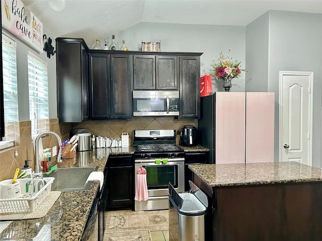 kitchen with a center island, tasteful backsplash, appliances with stainless steel finishes, stone countertops, and a sink