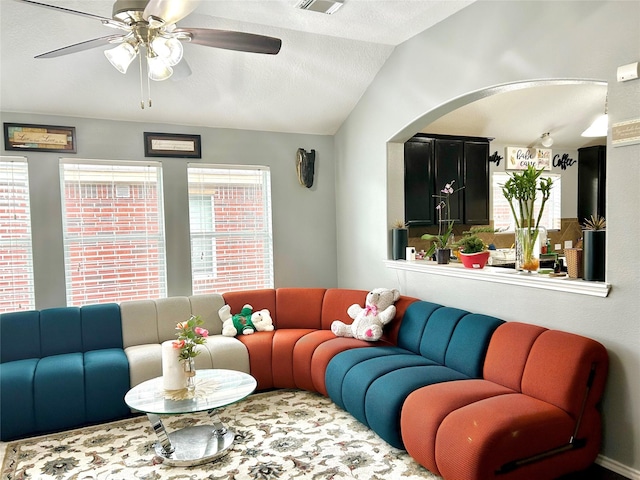 living area featuring vaulted ceiling, ceiling fan, and a textured ceiling