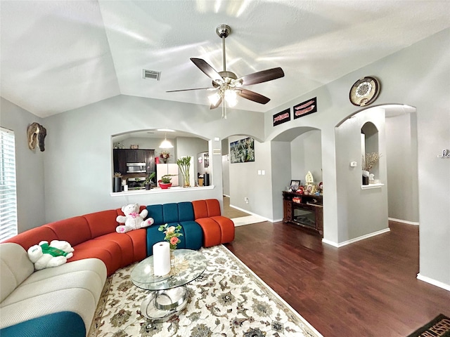 living area featuring wood finished floors, visible vents, baseboards, vaulted ceiling, and a ceiling fan