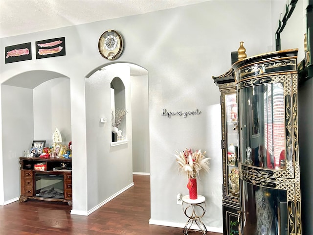 interior space with a textured ceiling, baseboards, and wood finished floors