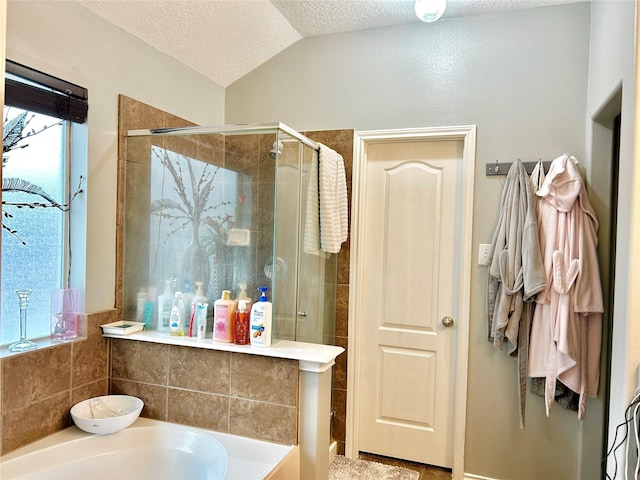 bathroom featuring a bath, a shower stall, vaulted ceiling, and a textured ceiling