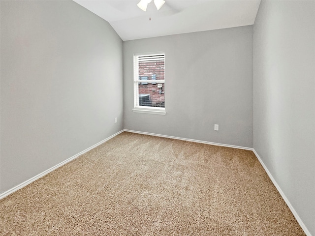 carpeted empty room with a ceiling fan, vaulted ceiling, and baseboards