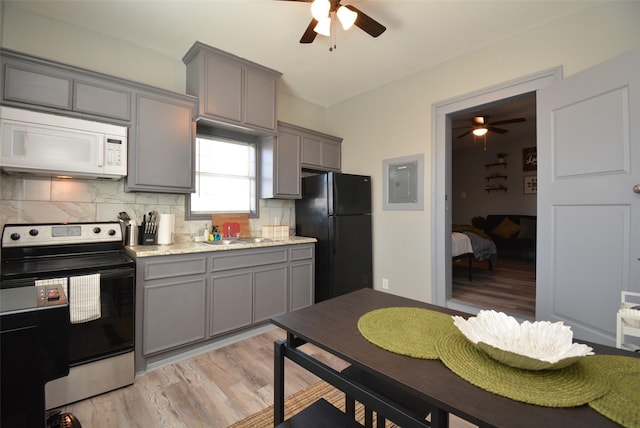 kitchen featuring white microwave, stainless steel electric range oven, freestanding refrigerator, and gray cabinetry