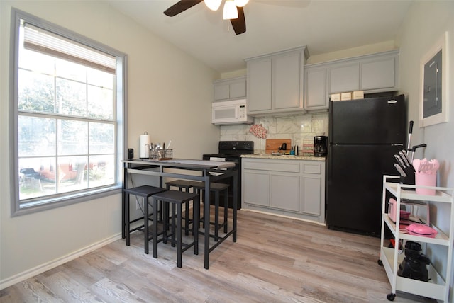 kitchen with light wood finished floors, decorative backsplash, ceiling fan, black appliances, and baseboards