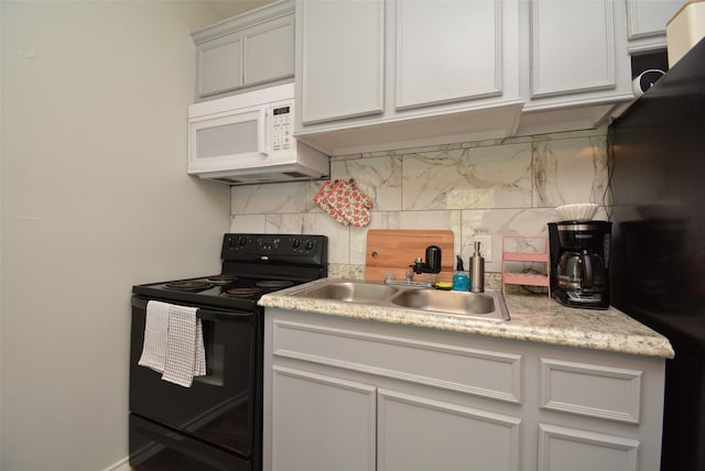 kitchen with black appliances, tasteful backsplash, a sink, and light countertops