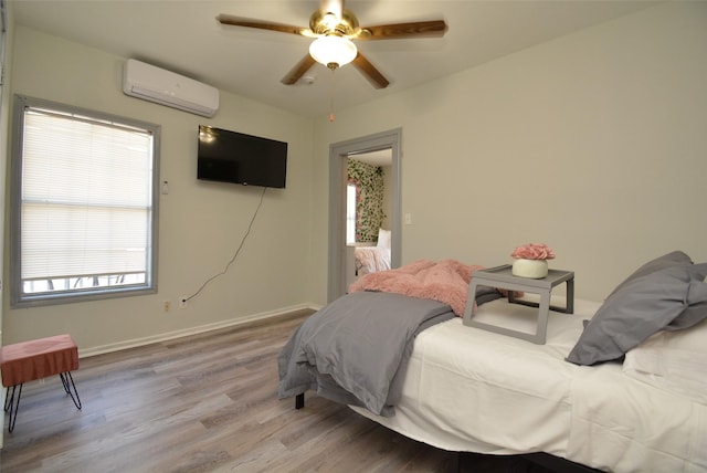 bedroom featuring ceiling fan, a wall mounted AC, wood finished floors, and baseboards