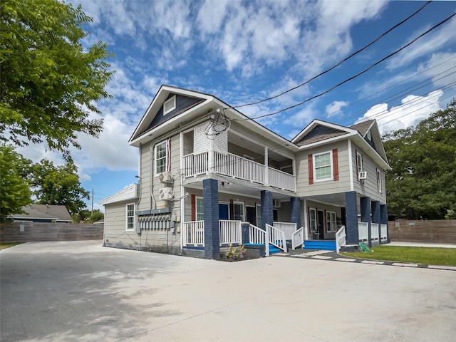 view of front of house with covered porch, concrete driveway, fence, and a balcony