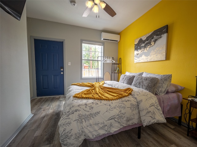 bedroom featuring a wall unit AC, wood finished floors, a ceiling fan, and baseboards