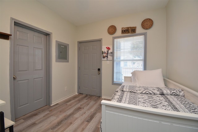 bedroom with light wood-type flooring, electric panel, and baseboards