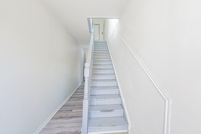 staircase featuring wood finished floors and baseboards