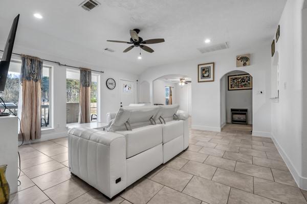 living room featuring visible vents, arched walkways, baseboards, ceiling fan, and recessed lighting